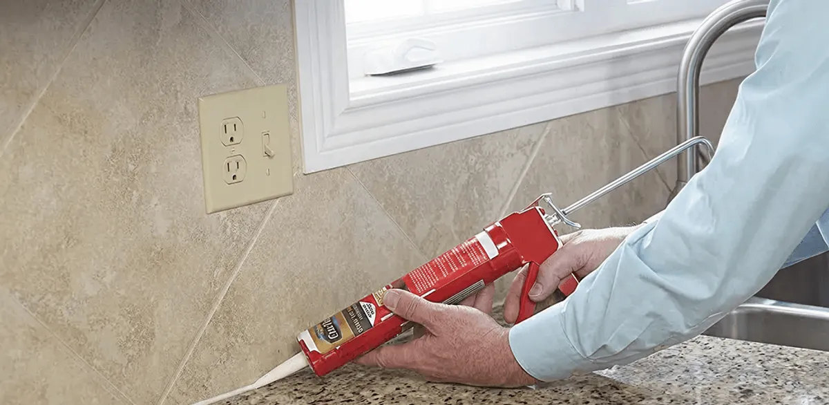 Handyman applying caulk along a kitchen backsplash and countertop seam in Jacksonville, FL